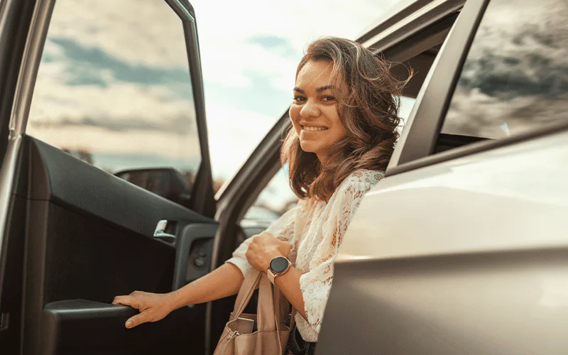 Mulher saindo de seu carro sorrindo