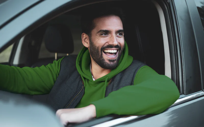 motorista sorrindo pela janela do carro