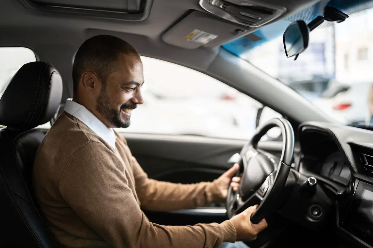 Homem dentro do carro segurando o volante