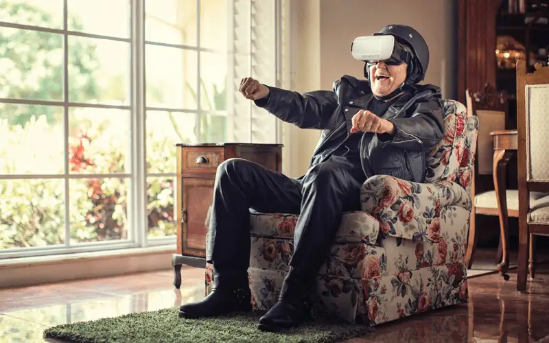 Senhor sentado na poltrona de sua casa usando um óculos de realidade virtual
