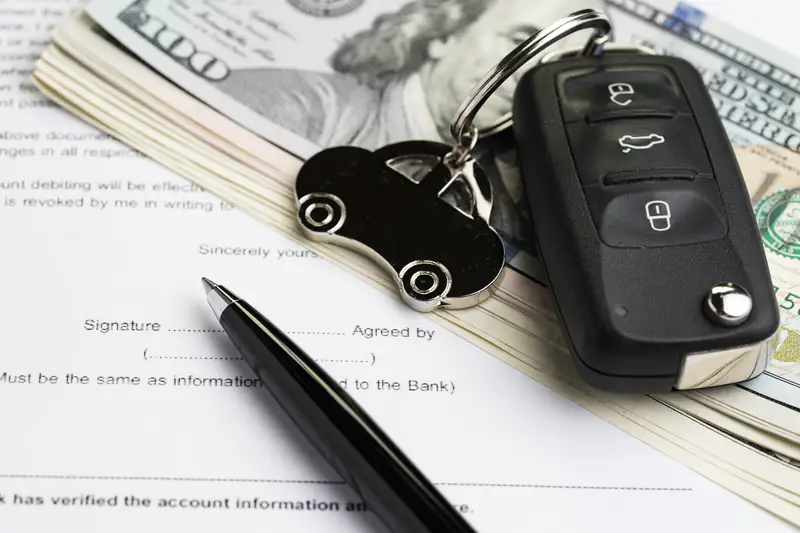 Preço de carro por assinatura: chave do carro em cima de alguns dólares e um contrato.