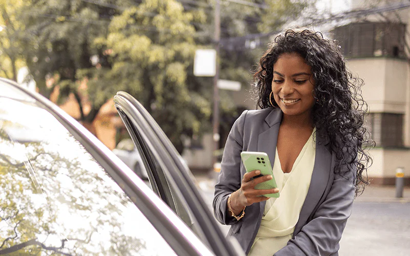 mulher abrindo porta do carro usando o celular para acessar ao app Localiza Meoo