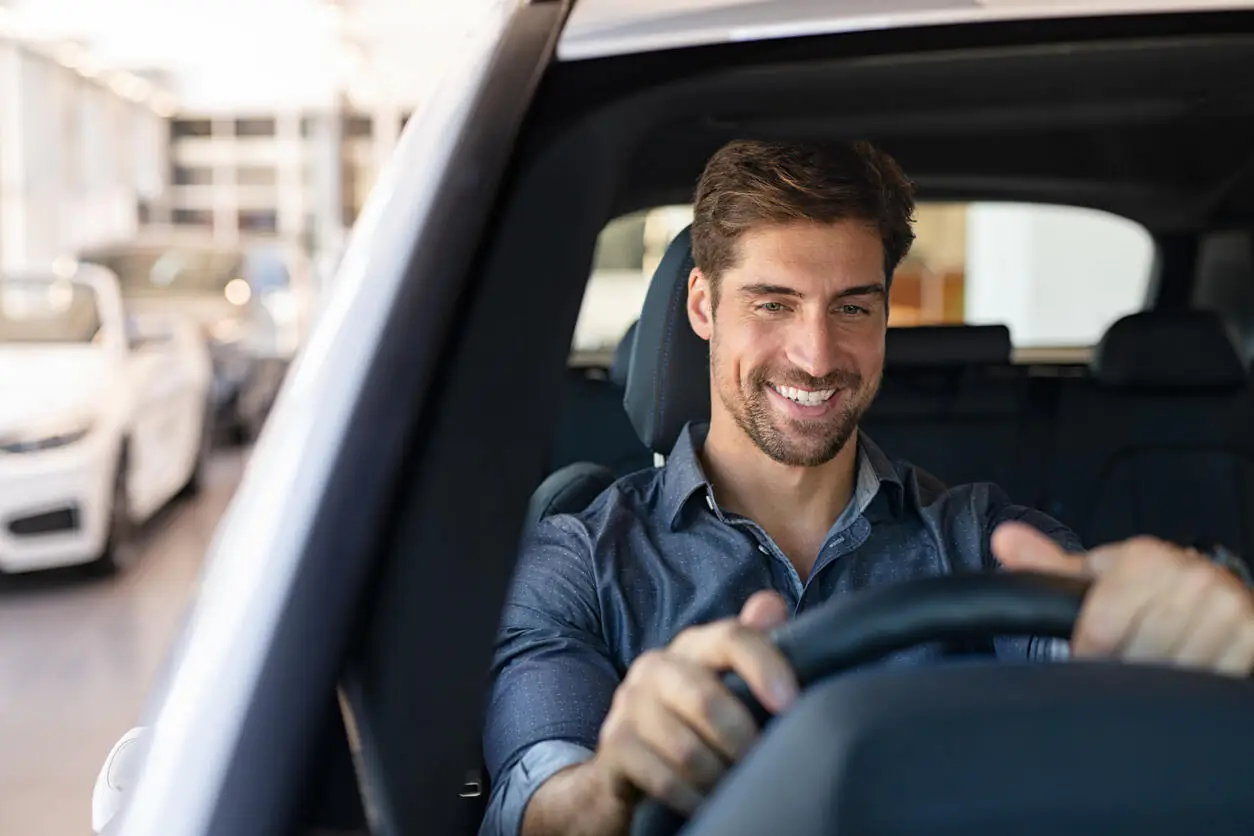 Imagem mostra um homem feliz dirigindo um carro