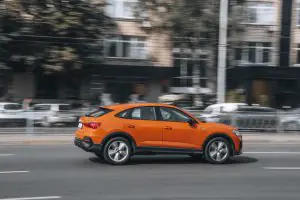 Carro Audi Q5 laranja movendo-se na rua