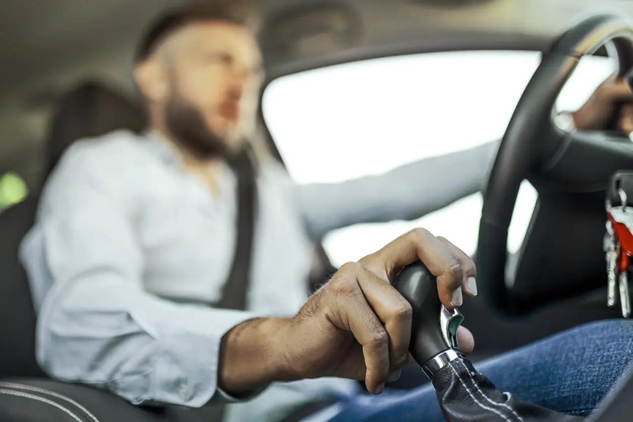 Homem dirigindo seu carro com mão no câmbio