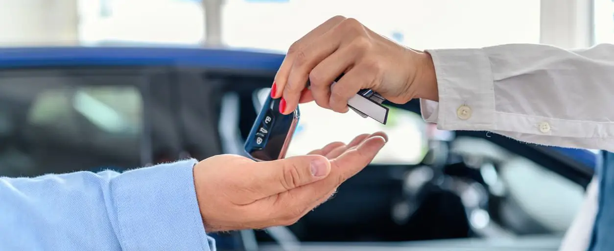 Pessoa devolvendo chave do carro por assinatura para vendedor.