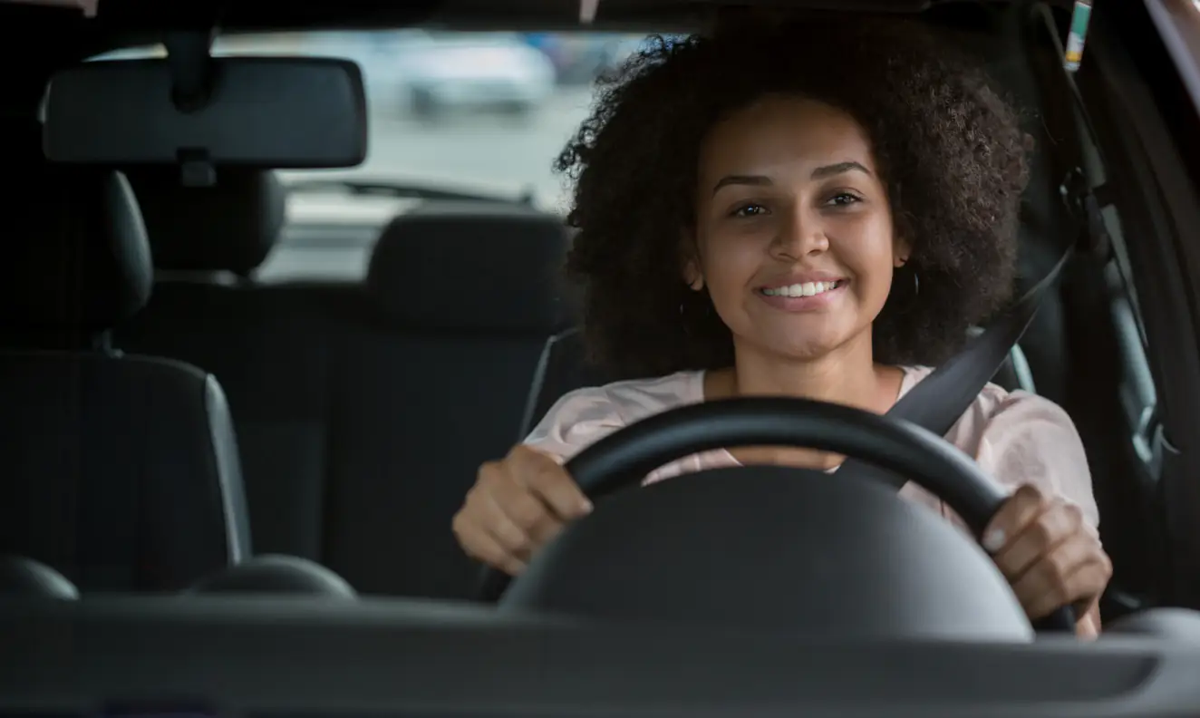 Mulher feliz dirigindo seu carro assinado