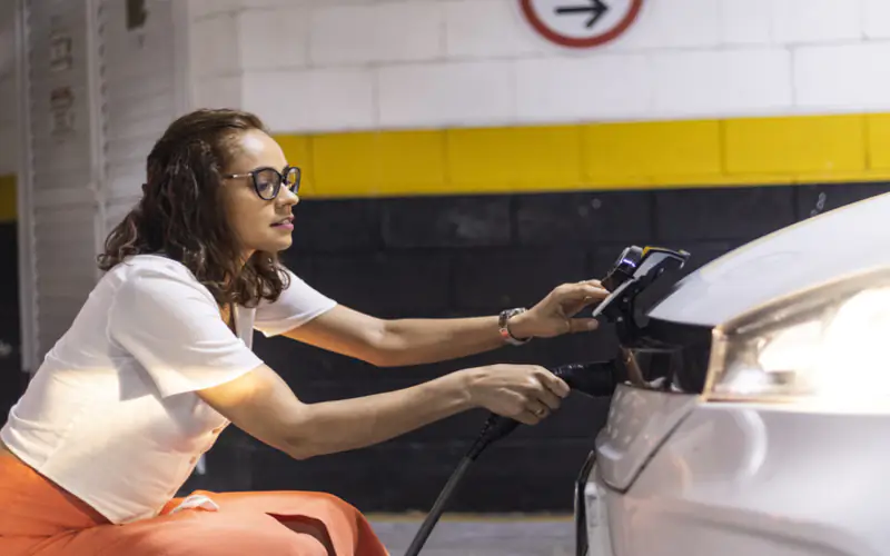 mulher abastecendo o carro elétrico